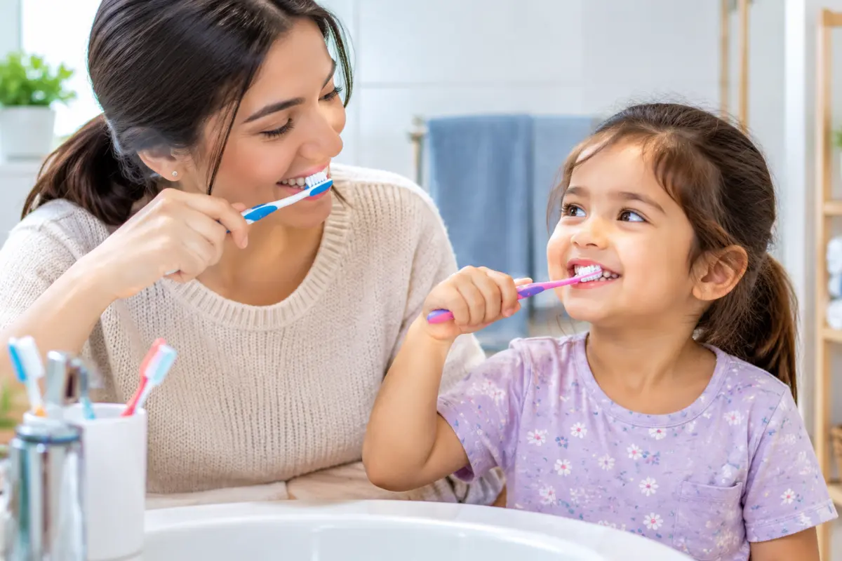 Mother and child brushing their teeth together