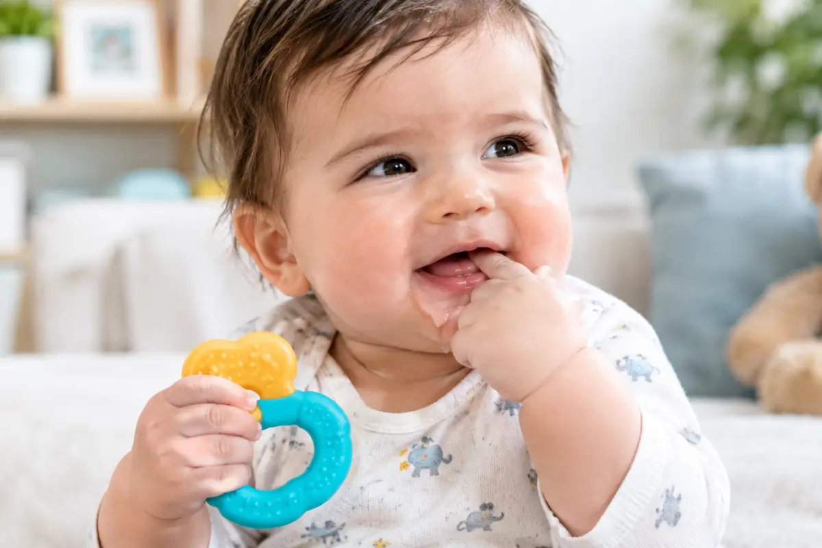 Baby showing common signs of teething while holding a teething toy